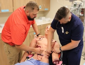 Dr. Garrett Feddersen and Zach Green practice tourniquet applications on the "Rescue Randy" moulage manikin.