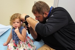 Dr. Garrett Feddersen using the otoscope to look into a child's ear.