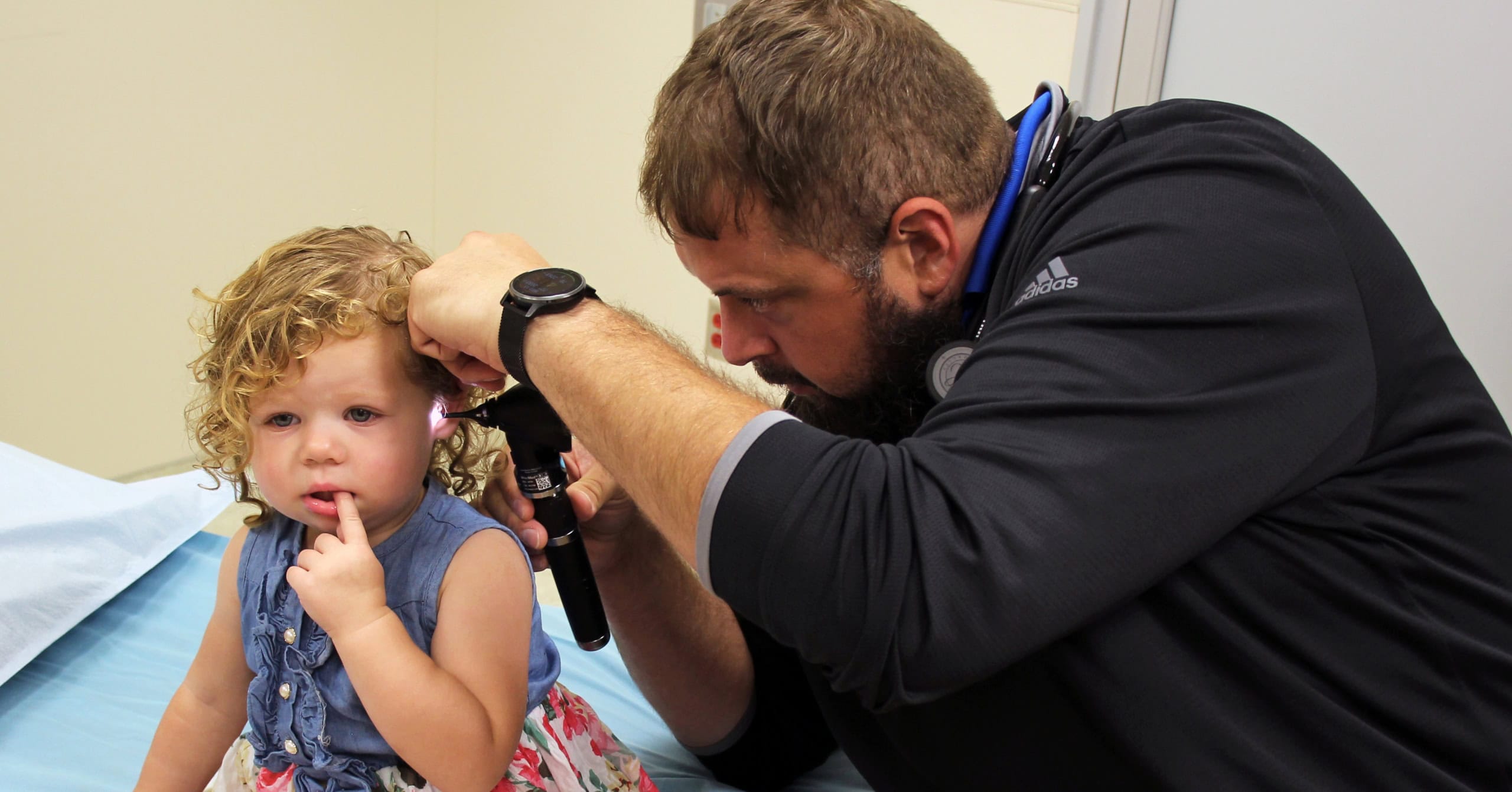 Dr. Garrett Feddersen using the otoscope to look into a child's ear.