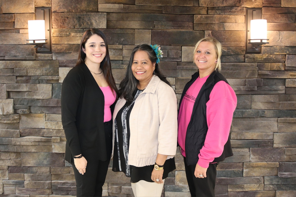 Three female BVRMC employees dressed in pink in front of brick wall at BVRMC