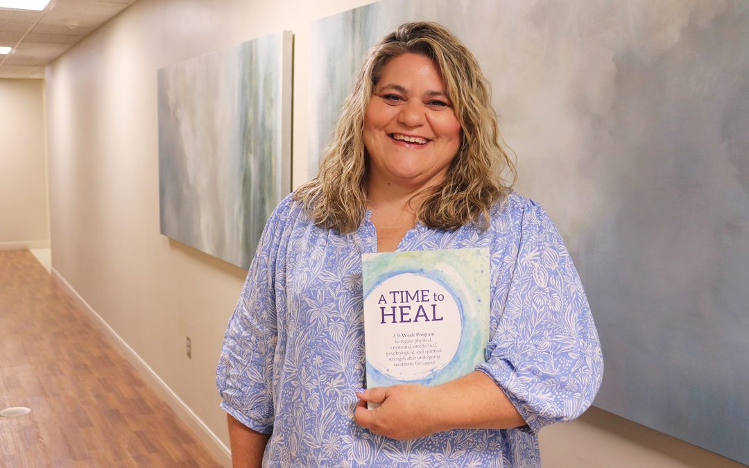 BVRMC Social Worker holding a book titled, "A Time to Heal" in a hallway at BVRMC.
